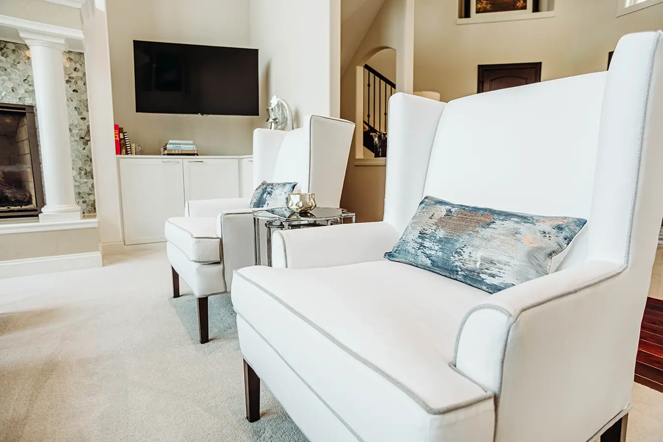 2 matching white armchairs with blue and white lumbar pillows