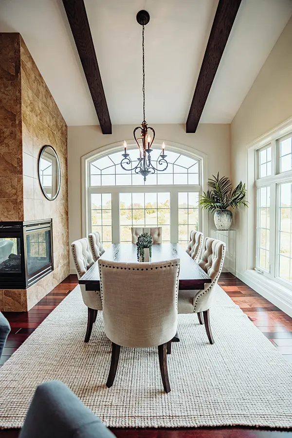 dining area with tall framed windows and dark ceiling beams