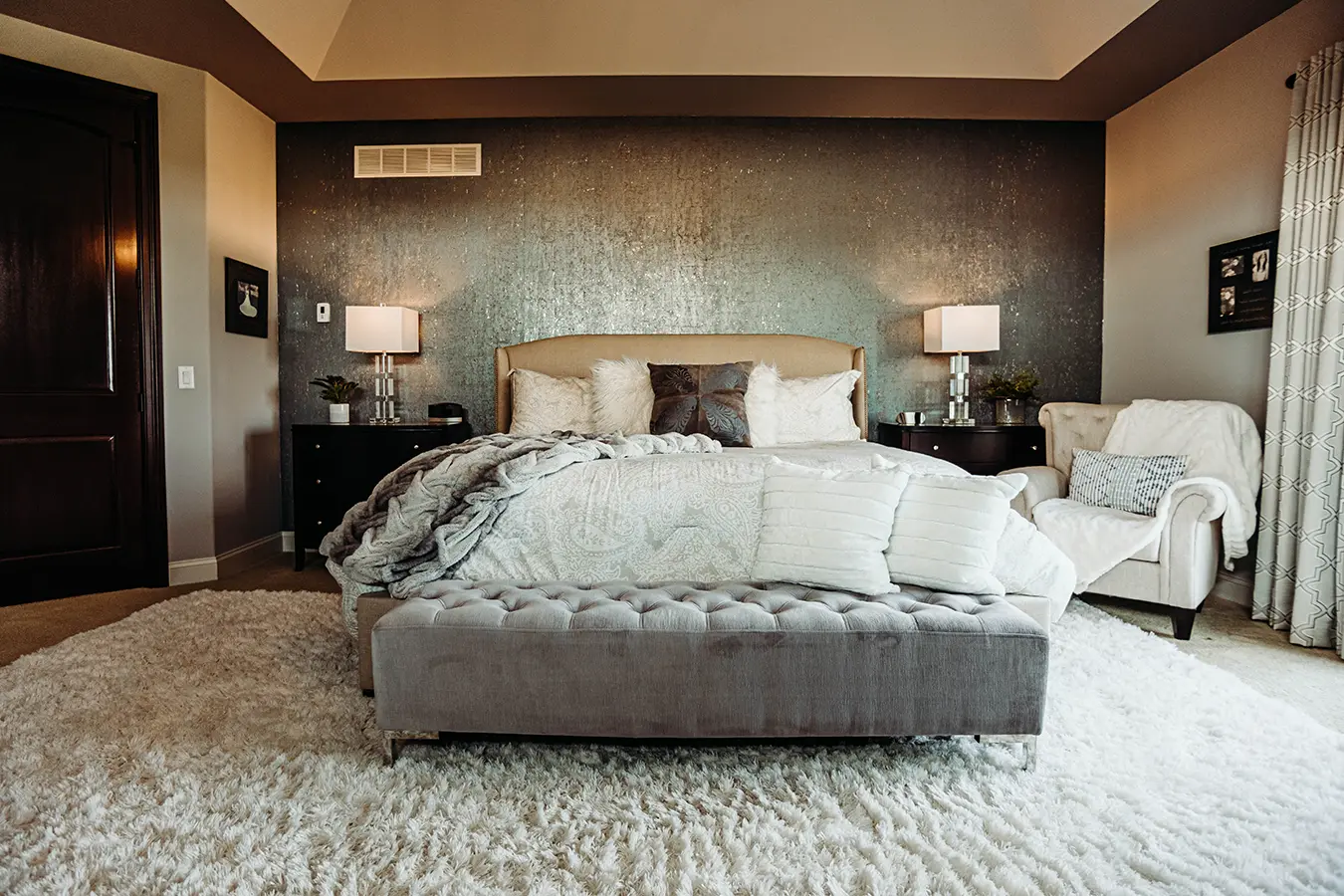 cozy bed with textured pillows, faux fur throw and patina walls