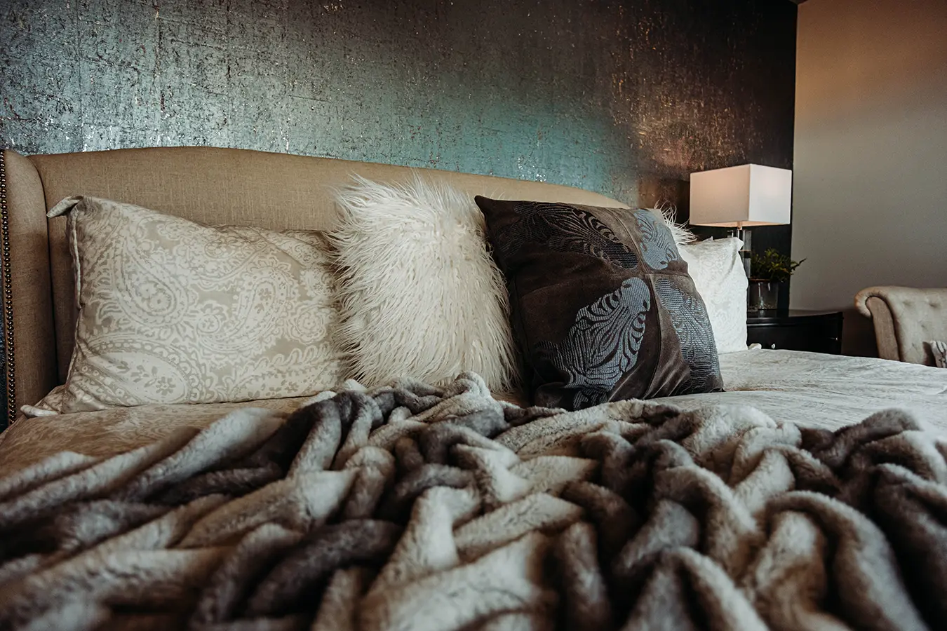 cozy bed with faux fur pillows and throw; patina wall